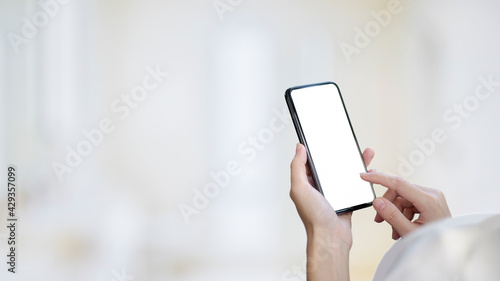Over shoulder close up view of female hands holding and touching on mock up smartphone screen