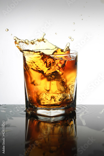 Studio shot of ice splashed onto a whiskey glass.