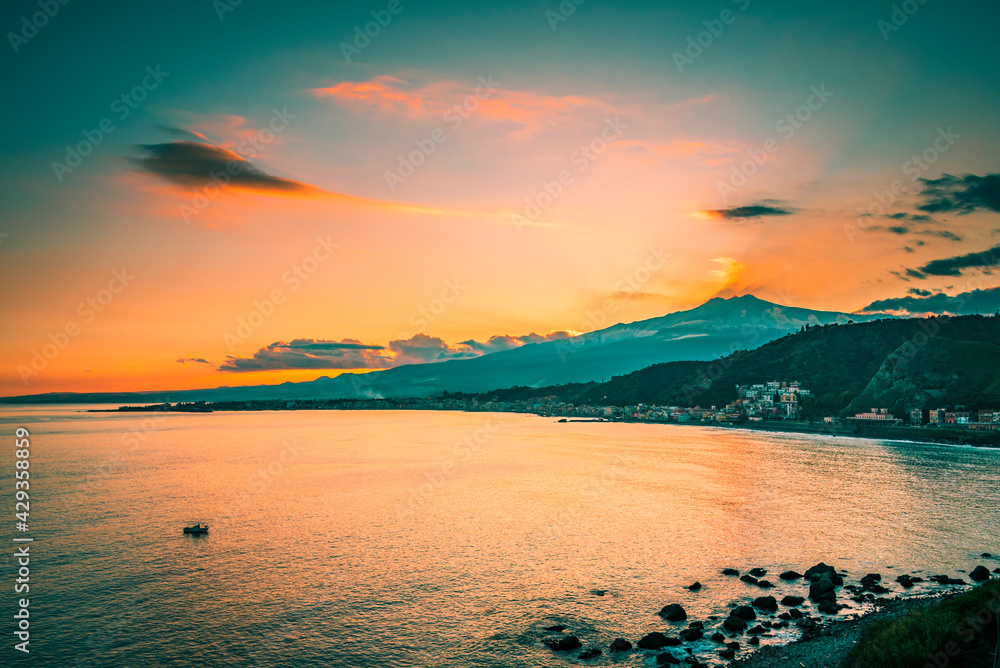 Silhouette of a mountain by the sea at sunset, teal and orange concept. Sunset on the coast of Giardini Naxos, Mt. Etna, Taormina, Sicily Silhouette of a mountain by the sea at sunset, teal and orange concept. Sunset on the coast of Giardini Naxos, Mt. Etna, Taormina, Sicily