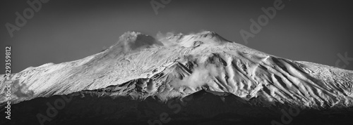 Black and white panorama of Mt. Etna covered by snow. Ash coming from the craters of Mt. Etna
