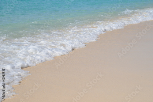 Tropical idyll, waves breaking gently on a golden beach on a sunny summers day.