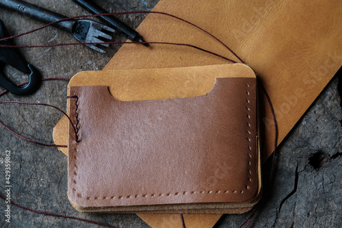 Genuine leather card holder wallet with tool on wood background