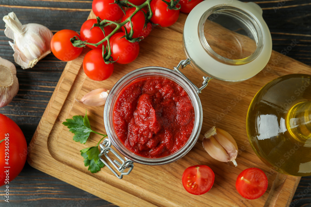 Jar with tomato paste on wooden table with ingredients Jar with tomato paste on wooden table with ingredients