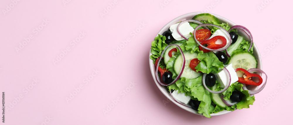 Bowl of greek salad on pink background