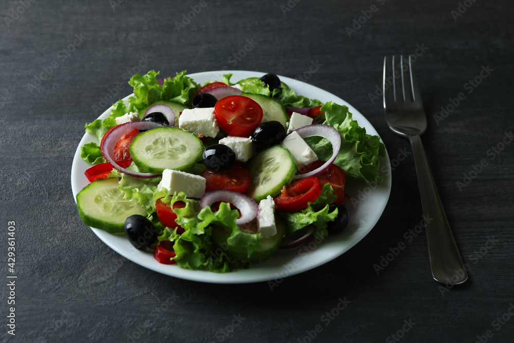 Plate of greek salad and fork on dark wooden background Plate of greek salad and fork on dark wooden background