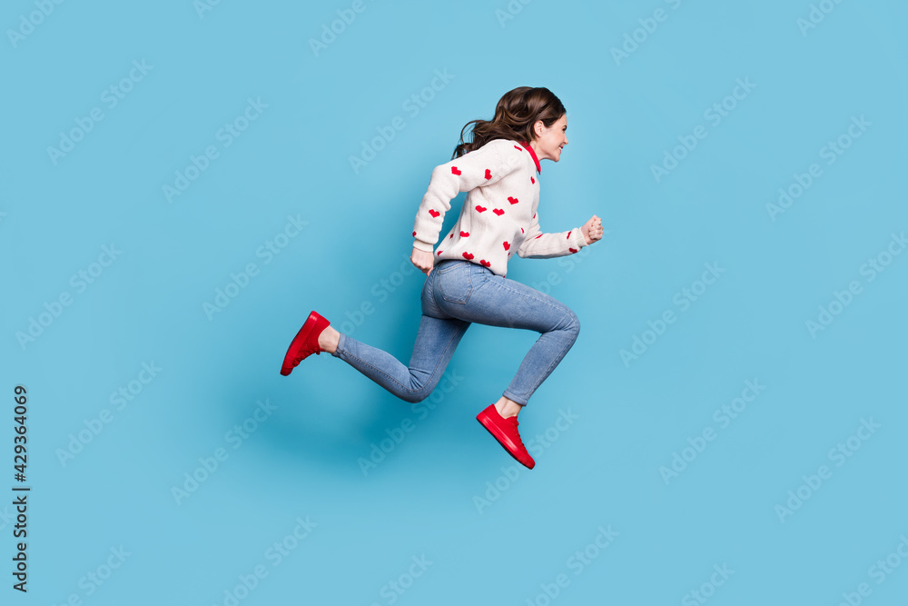 Full length photo of hurrying young lady wear hearts print sweater jumping running isolated blue color background