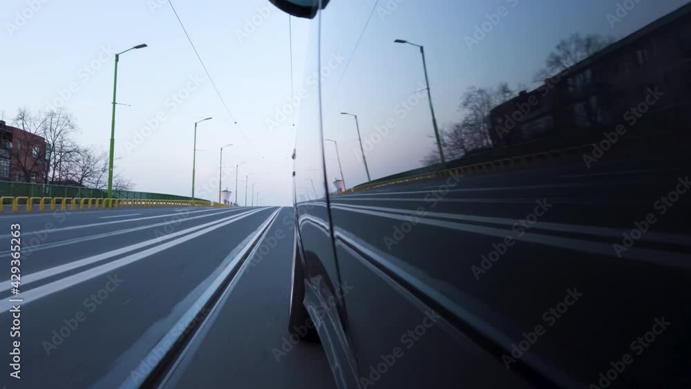 Generic car driving up a bridge in the city POV at sunset with oncoming traffic reflected in bodywork. Left side point of view from outside 4K real time no people Generic car driving up a bridge in the city POV at sunset with oncoming traffic reflected in bodywork. Left side point of view from outside 4K real time no people
