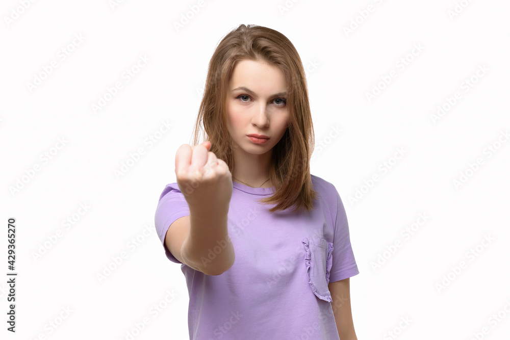 Angry serious girl looking at camera showing fist isolated on white background Angry serious girl looking at camera showing fist isolated on white background