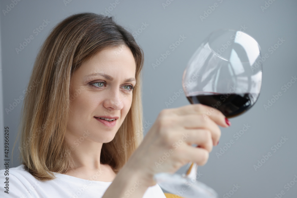 Young woman looking into glass with red wine Young woman looking into glass with red wine