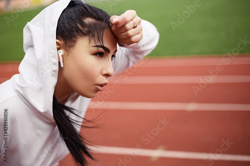 Running track treadmill, on the start. Sporty weary woman preparing for marathon triathlone. Female tired exhausted prostration runner training on the stadium. Image copy space photo