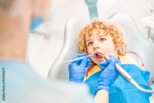 Pretty little boy in dental office  having his teeth checked by female dentist .
