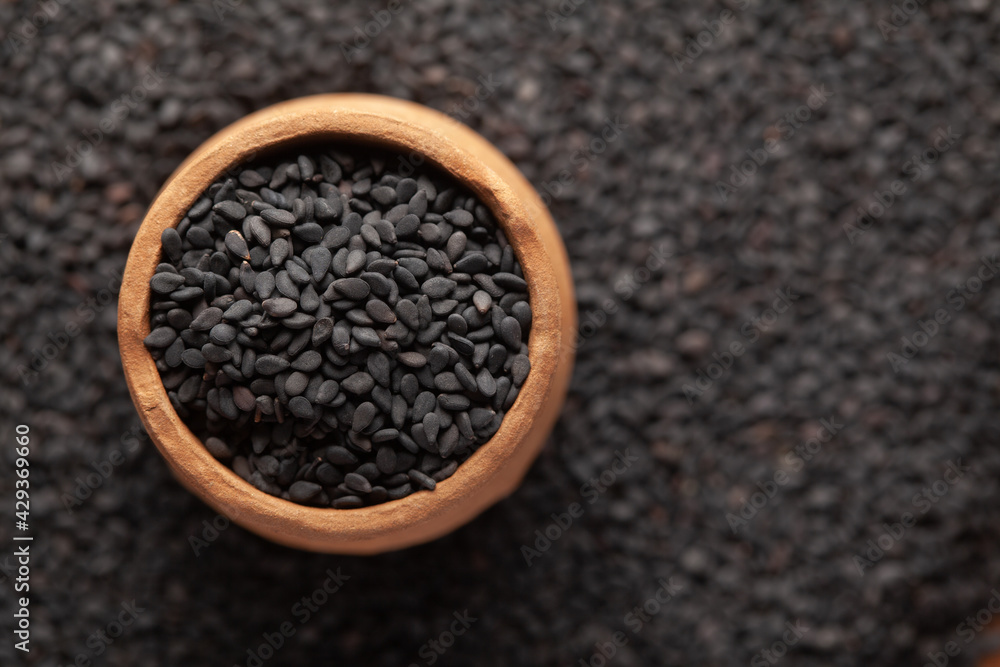 Macro Close-Up of Organic Black Sesame seeds (Sesamum indicum) or Black Til with shell in an earthen clay pot (kulhar) on the self background. Top view Macro Close-Up of Organic Black Sesame seeds (Sesamum indicum) or Black Til with shell in an earthen clay pot (kulhar) on the self background. Top view