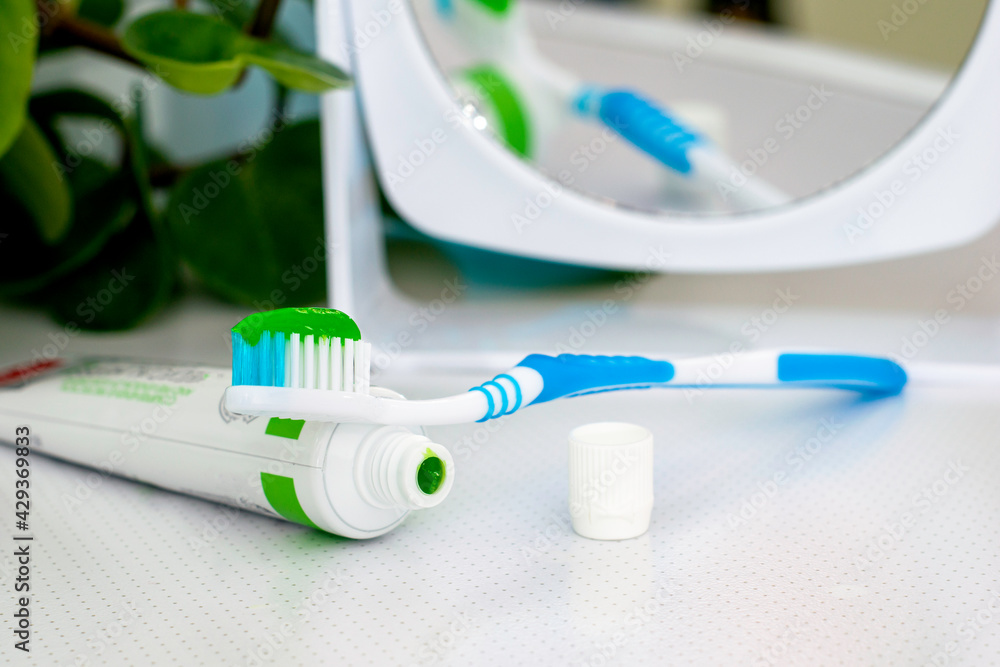 an open tube of toothpaste a toothbrush with applied toothpaste and a