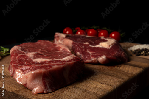 Raw marbled beef steak on a wooden cutting board. Top class marbled beef. Graphite-colored table top.