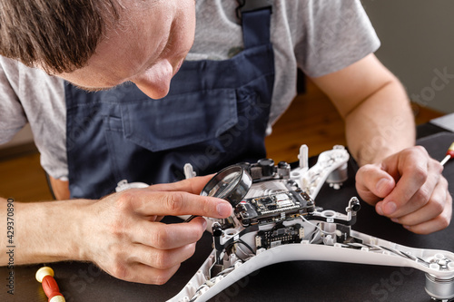 Close-up Of Person's Hand Repairing Drone Using Screwdriver. a man working in a repair shop