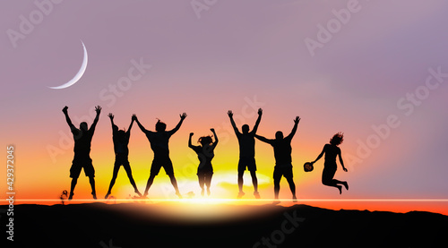 Silhouette of friends jumping at Sunset with crescent moon - Sand dune with Desert in the foreground 