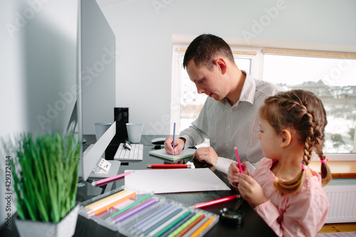 daughter draws with father sitting at the table