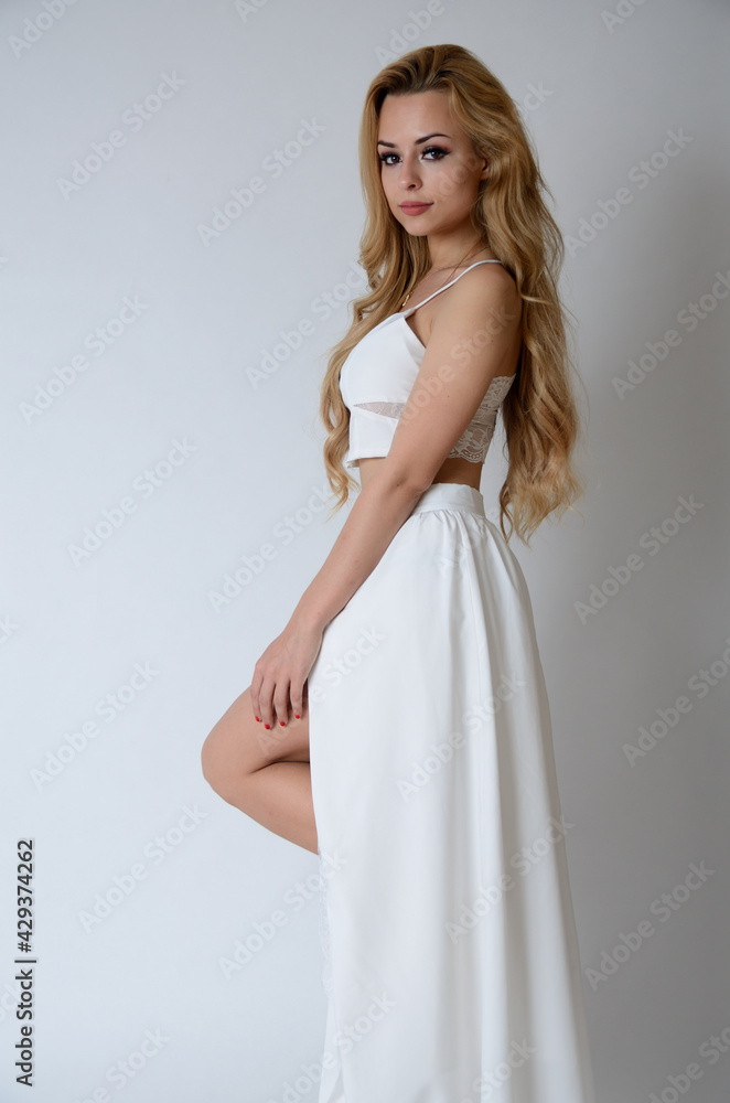 Fototapeta premium Polish model posing with white top, long white dress with cut, showing her legs.