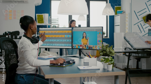 Fotografie Black retoucher woman analysing images on pc with two monitors and retouching digital assets with stylus pencil
