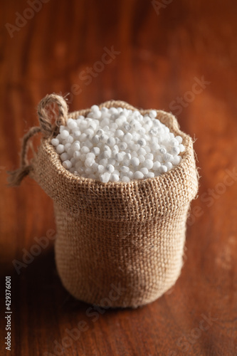 Close-up of organic white sago or sabudana big size in a standing jute bag over wooden brown background. photo