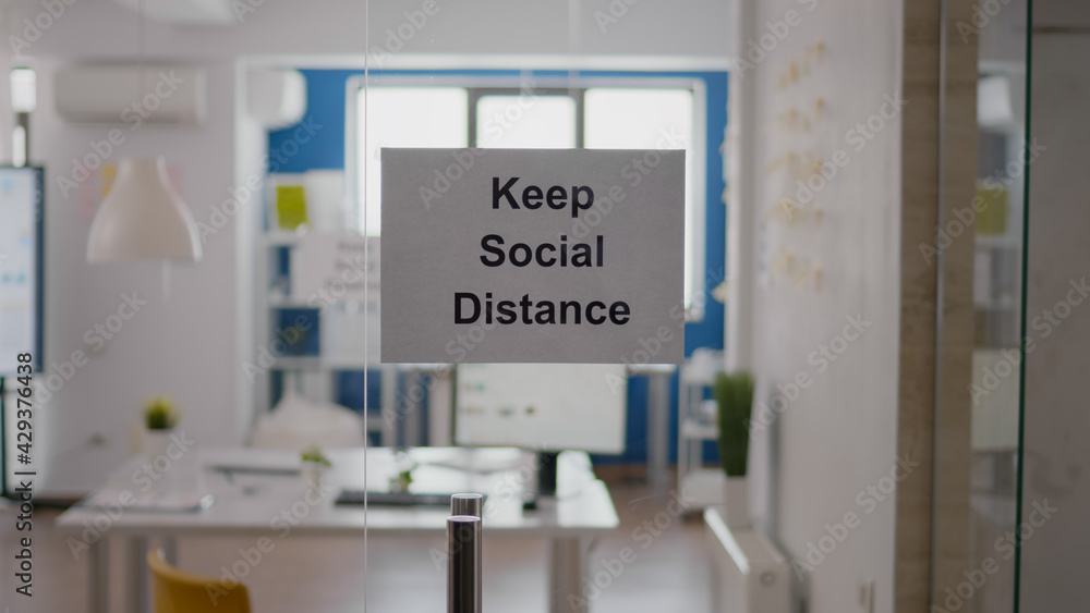 Business glass interior office with keep social distance sign on the wall. Modern office space with nobody in it during global pandemic, coronavirus crisis