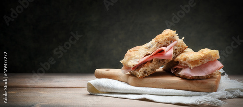 Focaccia with mortadella on old wooden table with cutting board and napkin, space for text. photo