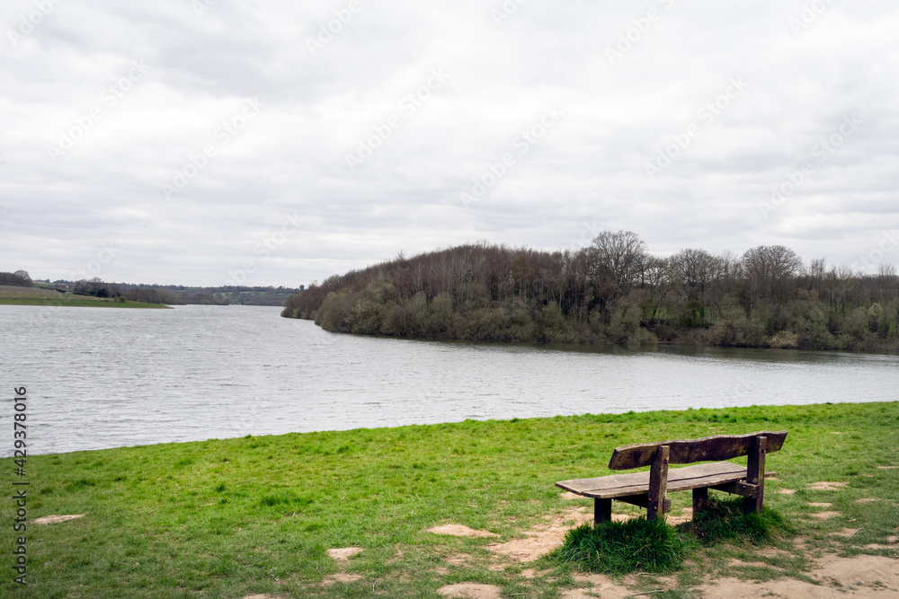 Wooden bench, empty, on the shore of Bewl water reservoir, South East England