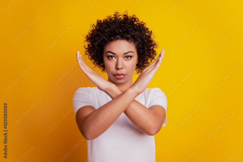 Portrait of young lady doing stop symbol over yellow background Portrait of young lady doing stop symbol over yellow background