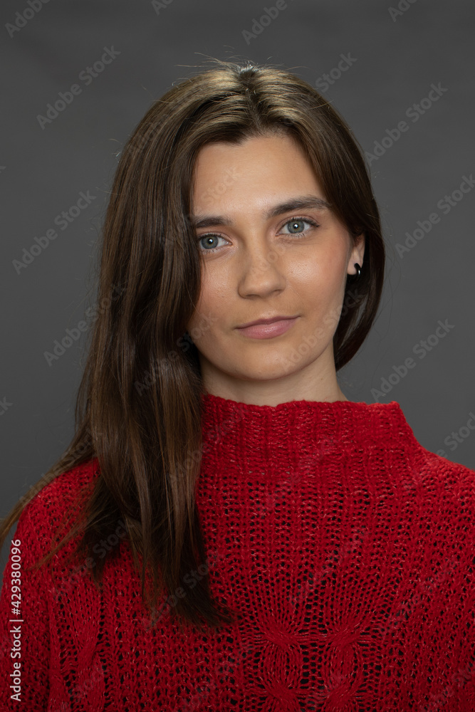 Young charming woman in red sweater looks at camera isolated on dark background. Concept of natural beauty, care, tenderness, skin hair cosmetics, no makeup, ecology female activist, woman business Young charming woman in red sweater looks at camera isolated on dark background. Concept of natural beauty, care, tenderness, skin hair cosmetics, no makeup, ecology female activist, woman business