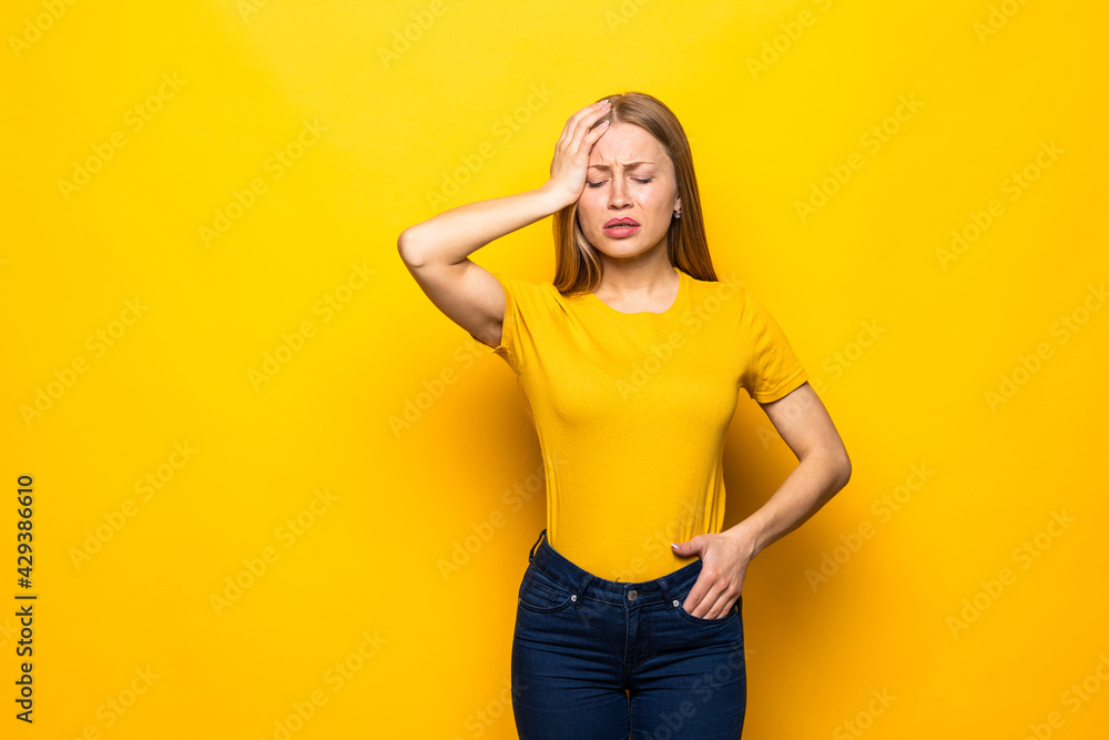 Young woman forgetting something, slapping forehead with palm and closing eyes isolated on a yellow background Young woman forgetting something, slapping forehead with palm and closing eyes isolated on a yellow background