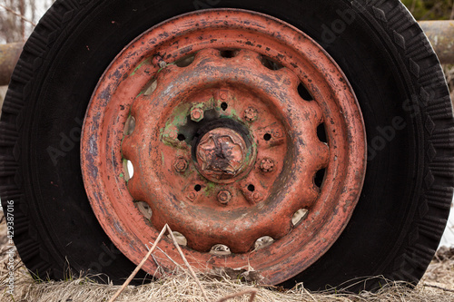 Tractor wheel with red rust and black rubber tire
