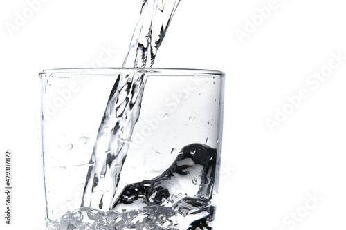 Glass of water being filled. Close up pouring clear water in transparent drinking glass over white background