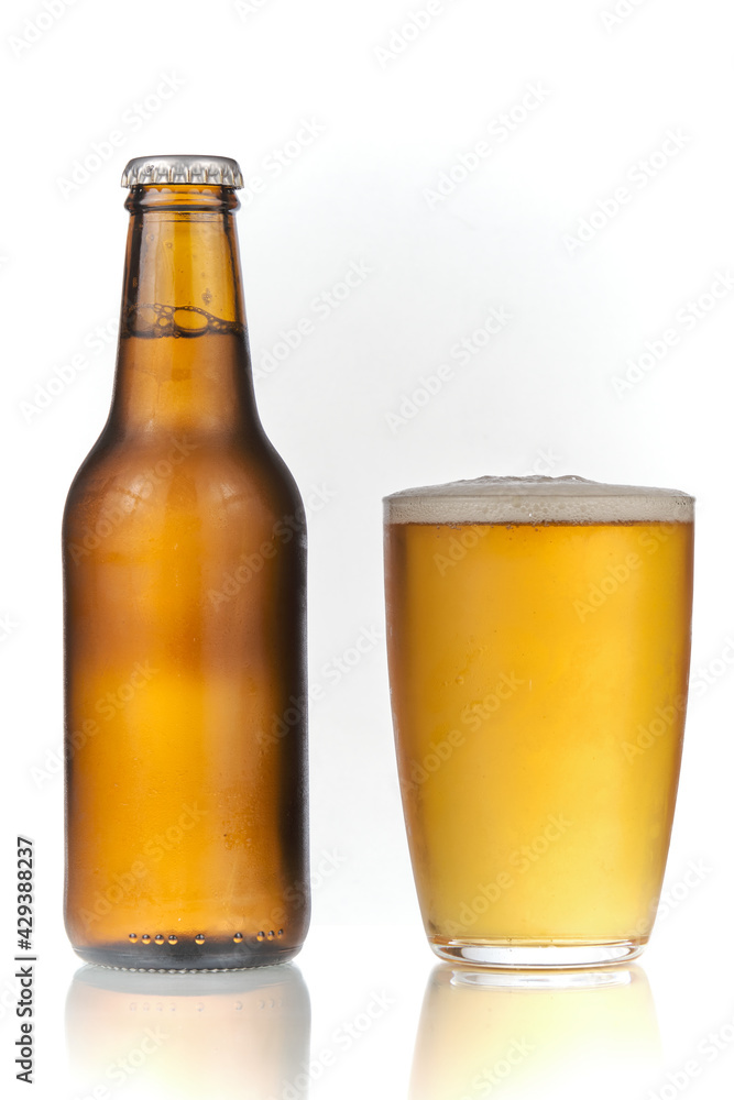 Brown beer bottle and a glass of beer in a white background. Beer brown bottle with drops and a full glass of beer isolated in white background