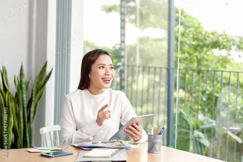 Smiling young woman reading something on the tablet and sitting near the windowsill at home Free Download Smiling young woman reading something on the tablet and sitting near the windowsill at home - GFXLoad