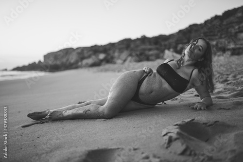 Chica guapa morena española en el sur de españa en una cala natural con piedras y olas salvajes disfrutando de un atardecer calido de verano 