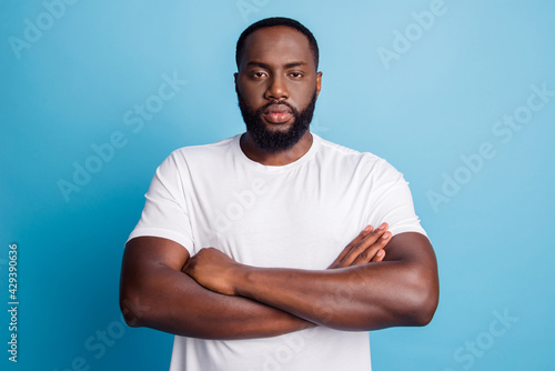 Fotografie Serious african businessman standing with arms folded on blue wall