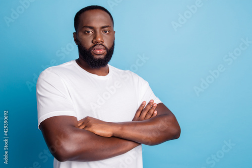 African businessman standing with arms crossed look camera on blue background