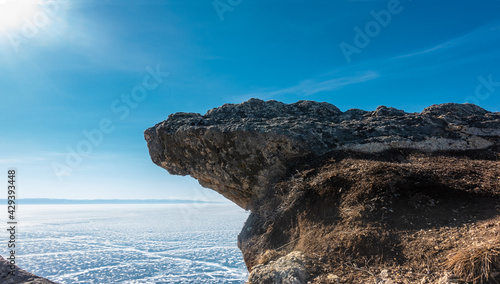 фотографія A flat rock overhang  a frozen lake against a blue sky