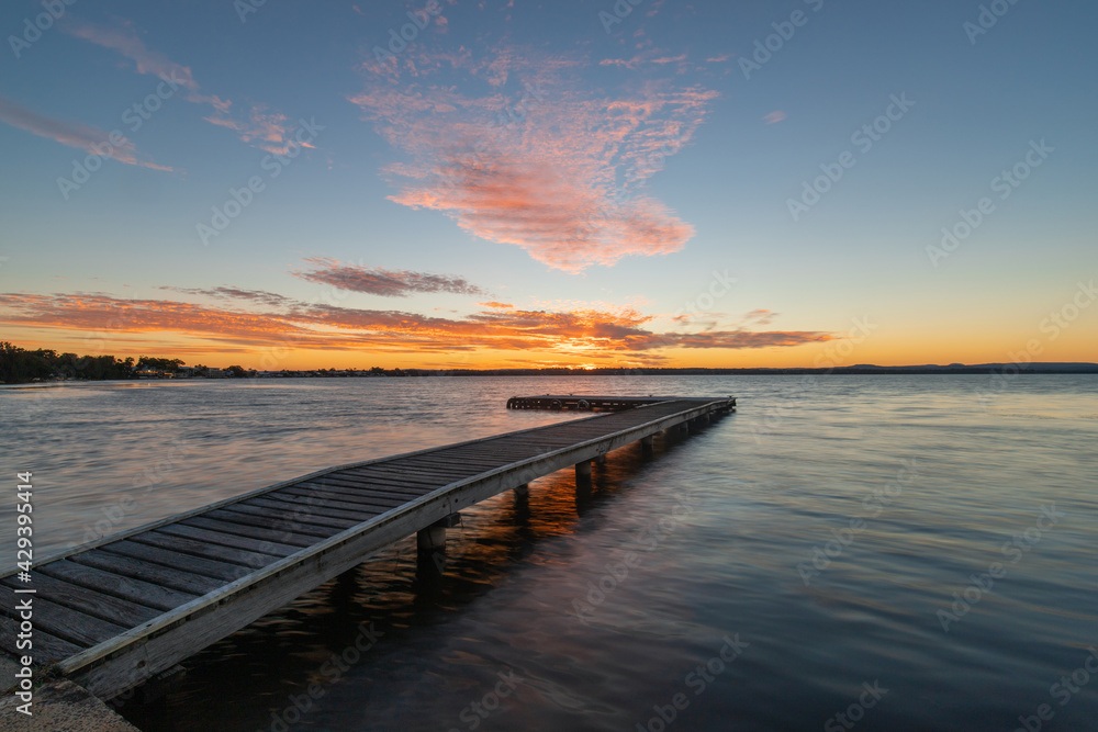 Obraz premium Empty pier on the lake at sunset time.