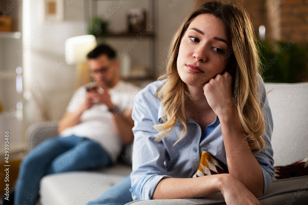 Couple at home after having a fight. Sad depressed woman sitting on sofa.. Couple at home after having a fight. Sad depressed woman sitting on sofa..