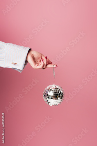 Cropped view of young woman holding disco ball isolated on pink