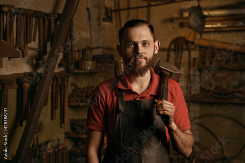 Blacksmith with hammer in workshop closeup portrait