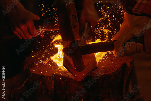 Obraz na plátne Blacksmiths hit molten metal with hammers close up