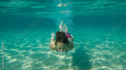 A Girl Swimming Above The Sandy Sea Bottom In The Beautiful Turquoise Water.