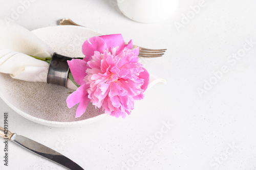 Elegance romantic table setting with pink peony flowers on a white table. Close up. Copy space.