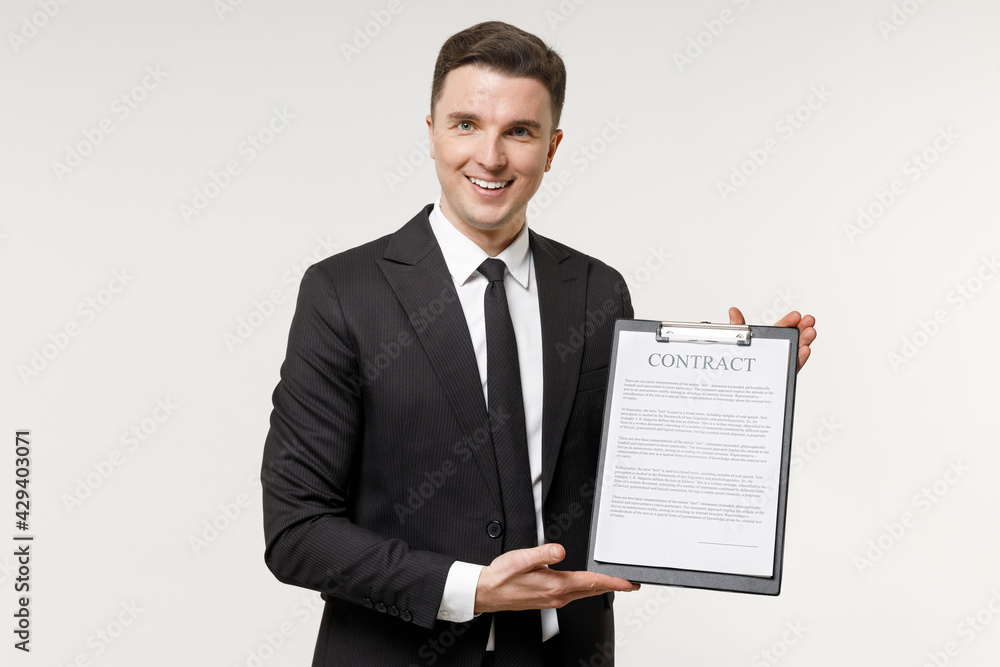 Young happy employee business corporate lawyer man in classic formal black grey suit shirt tie work in office hold clipboard with paper document contract agreement isolated on white background studio. Young happy employee business corporate lawyer man in classic formal black grey suit shirt tie work in office hold clipboard with paper document contract agreement isolated on white background studio.
