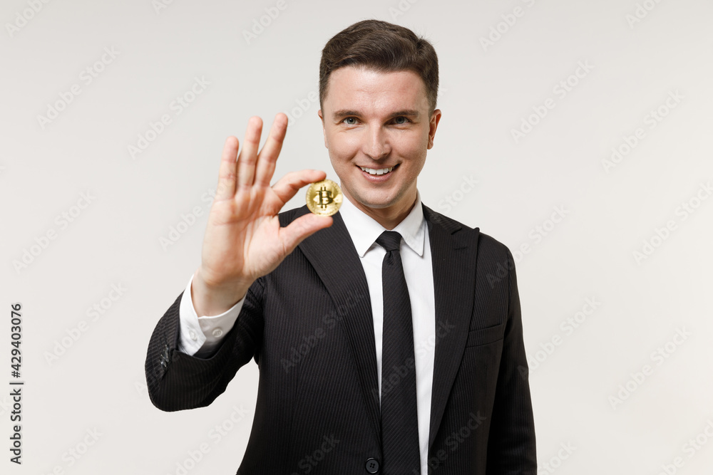 Young happy rich successful employee business corporate lawyer man 20s wear classic black grey suit shirt tie work in office holding bitcoin coin currency isolated on white background studio portrait. Young happy rich successful employee business corporate lawyer man 20s wear classic black grey suit shirt tie work in office holding bitcoin coin currency isolated on white background studio portrait.