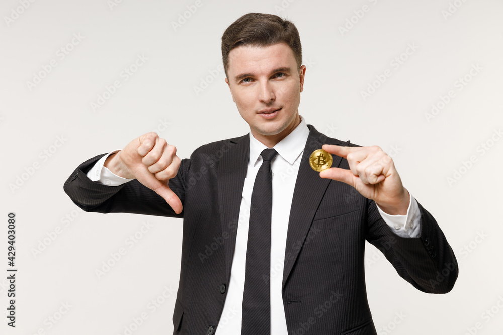 Young sad employee business corporate lawyer man in classic black grey suit shirt tie work in office holding bitcoin coin currency show thumb down gesture isolated on white background studio portrait. Young sad employee business corporate lawyer man in classic black grey suit shirt tie work in office holding bitcoin coin currency show thumb down gesture isolated on white background studio portrait.
