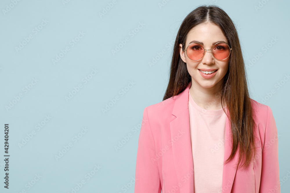 Young fun smiling happy cheerful caucasian trendy stylish fashionable woman 20s wear pastel pink clothes glasses looking camera isolated on blue background studio portrait. People lifestyle concept. Young fun smiling happy cheerful caucasian trendy stylish fashionable woman 20s wear pastel pink clothes glasses looking camera isolated on blue background studio portrait. People lifestyle concept.