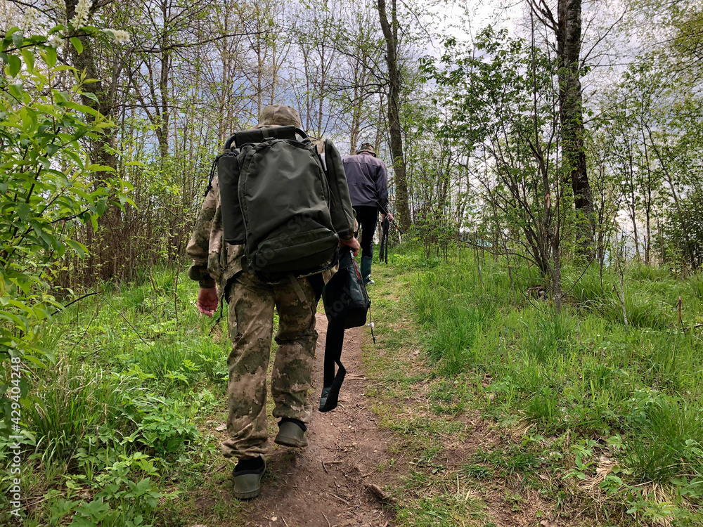 Fishermen lift with backpacks and fishing rods, return home after fishing. Fishermen lift with backpacks and fishing rods, return home after fishing.